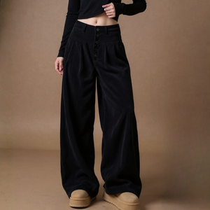 Person wearing black wide-leg pants and beige shoes on a brown background