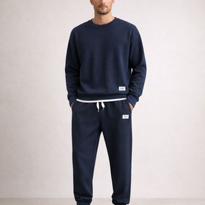 Person wearing a navy tracksuit with white drawstrings on a plain background