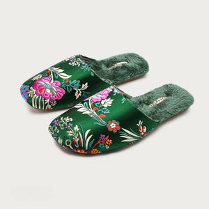 Pair of green floral slippers on a light gray background
