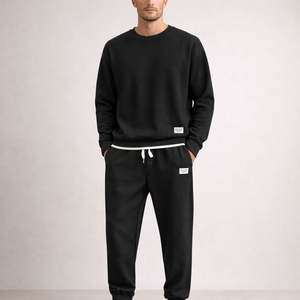 Person wearing a black tracksuit with white drawstrings on a light gray background