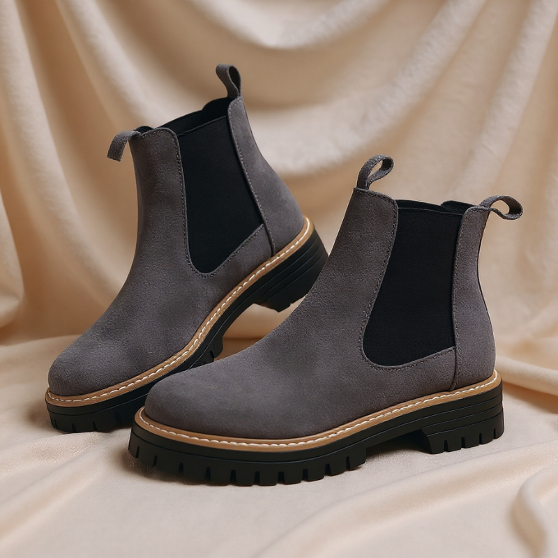 Pair of gray Chelsea boots on a beige fabric background