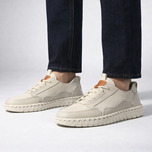 Beige sneakers worn with dark jeans on a light gray background