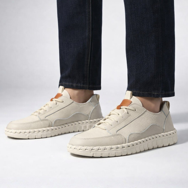Beige sneakers worn with dark jeans on a light gray background