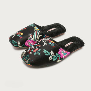 Pair of black slippers with colorful floral embroidery on a light gray background