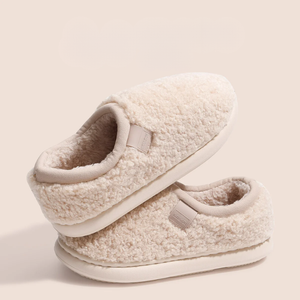 Pair of cream-colored slippers with fleece lining on a light beige background