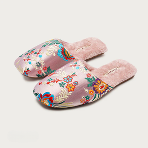 Pair of pink slippers with floral patterns on a white background