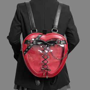 Red heart-shaped backpack with black straps and bow on a person wearing a black outfit.