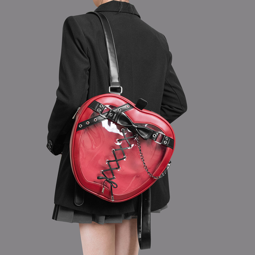 Person wearing a black coat with a red heart-shaped backpack on a gray background