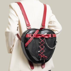 Black heart-shaped backpack with red accents worn by a person in a white coat.