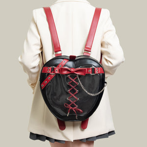 Person wearing a black backpack with red accents and a bow, standing against a plain background.
