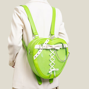 Person wearing a bright green backpack with a white bow and chain detail on a plain background