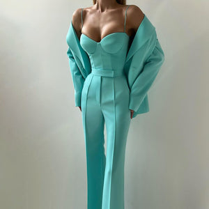 Teal jumpsuit worn by a model against a plain background
