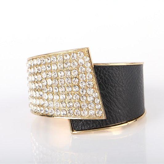 Black leather cuff with gold and crystal embellishments on a white background