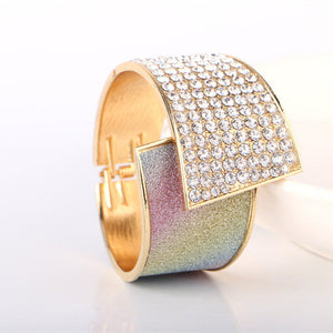 Gold and iridescent bracelet with diamond-like stones on a white background