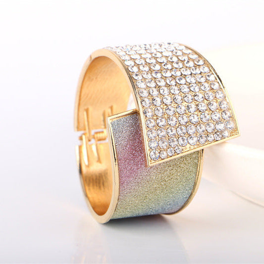 Gold and iridescent bracelet with diamond-like stones on a white background