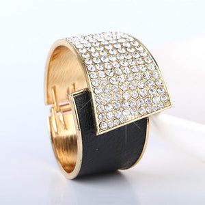 Gold and black bracelet with diamond-like stones on a white background