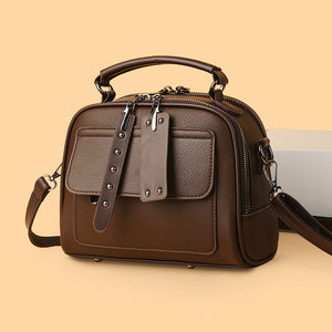 Brown leather handbag with a strap on a beige background