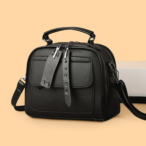 Black handbag with a strap on a beige background