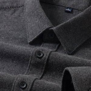 Close-up of a dark gray textured shirt with buttons and a brand label.