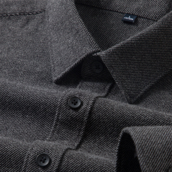 Close-up of a dark gray textured shirt with buttons and a brand label.