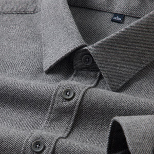 Close-up of a gray shirt with button details and a brand label.