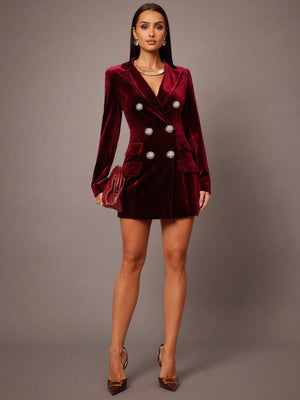 Woman wearing a burgundy velvet blazer dress against a gray background