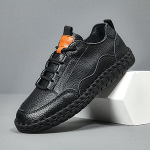 Black leather sneaker with orange accents on a gray background