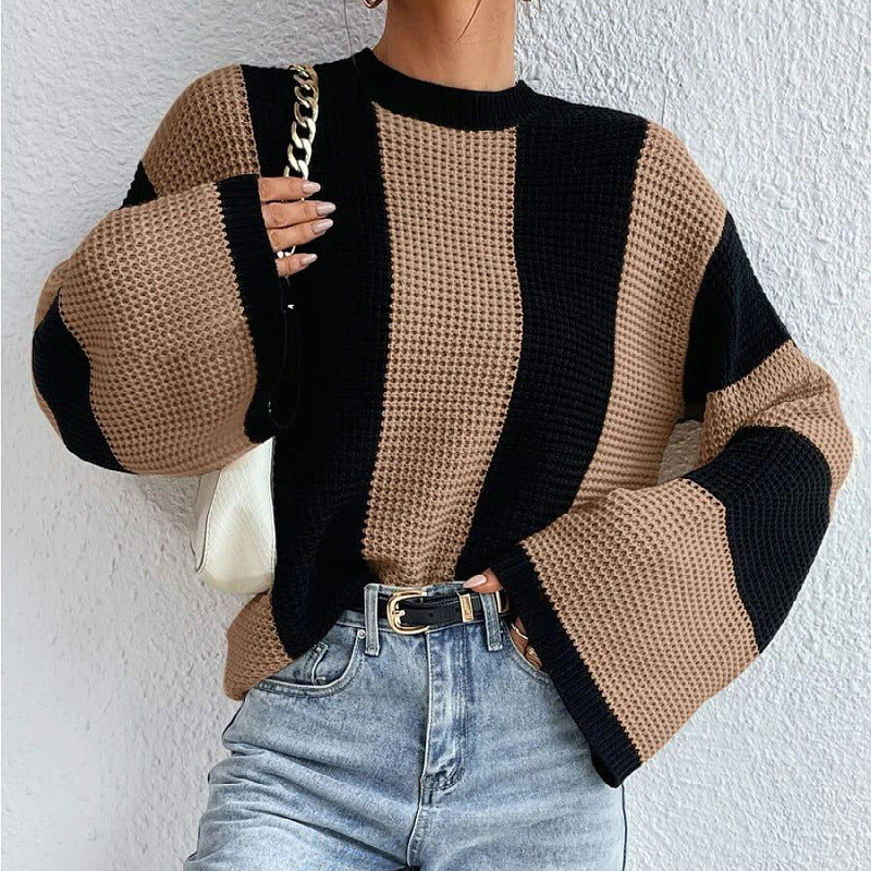 Person wearing a black and white striped sweater with a neutral background