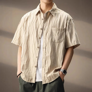 Person wearing a beige striped shirt with a neutral background