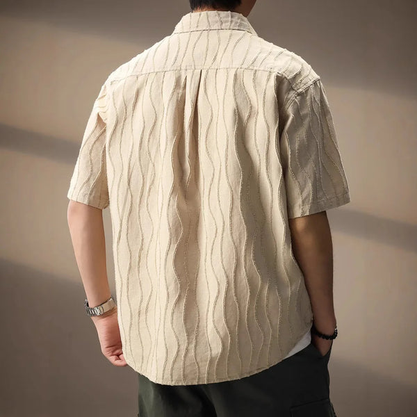 Person wearing a beige textured shirt against a neutral background