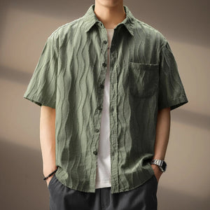 Person wearing a green textured shirt with a plain background