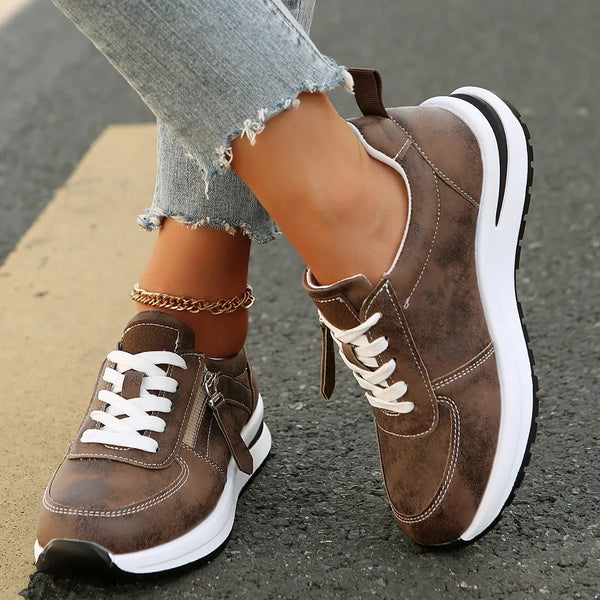 Brown sneakers with white soles worn by a person on a street.