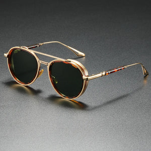 Gold-framed sunglasses with dark lenses on a gray surface