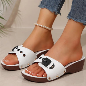 White sandals with brown soles worn by a person on a neutral background
