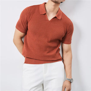Person wearing a rust-colored knitted polo shirt and white pants on a light gray background