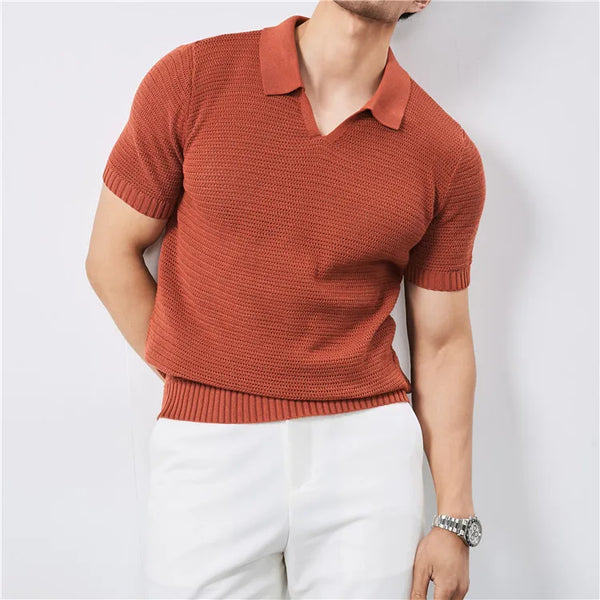 Person wearing a rust-colored knitted polo shirt and white pants on a light gray background
