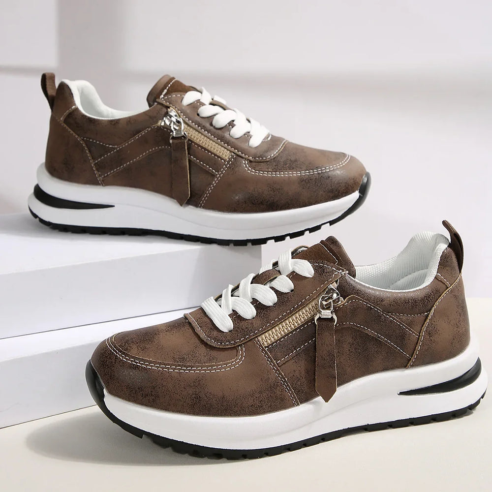 Brown sneakers with white laces on a light gray background
