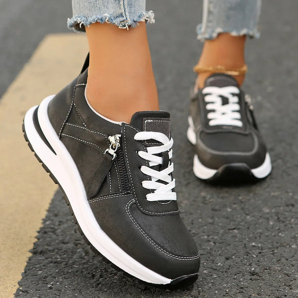 Black sneakers with white soles worn on a road surface