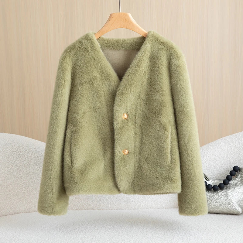 Green cardigan on a hanger against a beige background