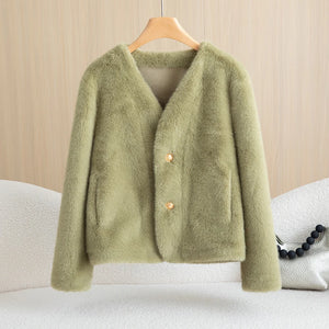 Green cardigan on a hanger against a beige background