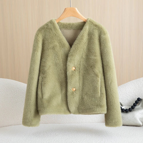Green cardigan on a hanger against a beige background