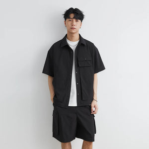 Person wearing a black shirt and shorts set against a white background