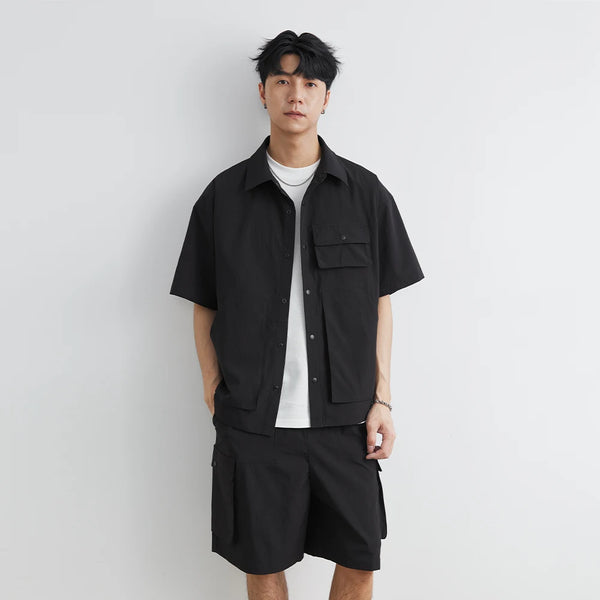 Person wearing a black shirt and shorts set against a white background