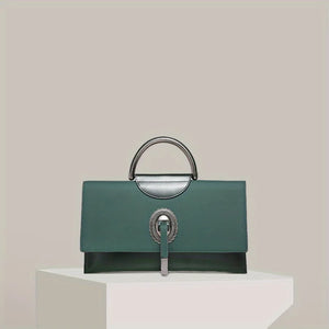 Green handbag with silver accents on a white pedestal against a light beige background