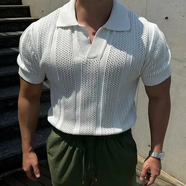 Person wearing a white knit polo shirt and green pants outdoors.
