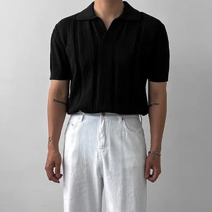 Person wearing a black short-sleeve shirt and white pants against a plain background