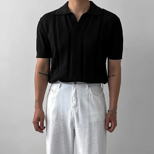 Person wearing a black short-sleeve shirt and white pants against a plain background