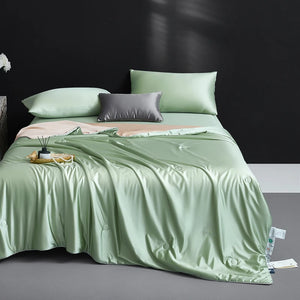 Bed with light green bedding and pillows against a dark wall