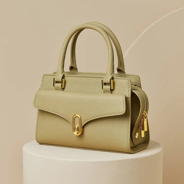 Green handbag with gold accents on a beige background