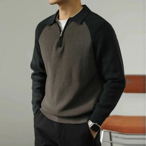 Person wearing a black and gray sweater with a blurred background